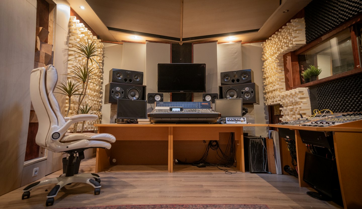 Sala de control de estudio de grabación musical con mesa de mezclas y monitores.