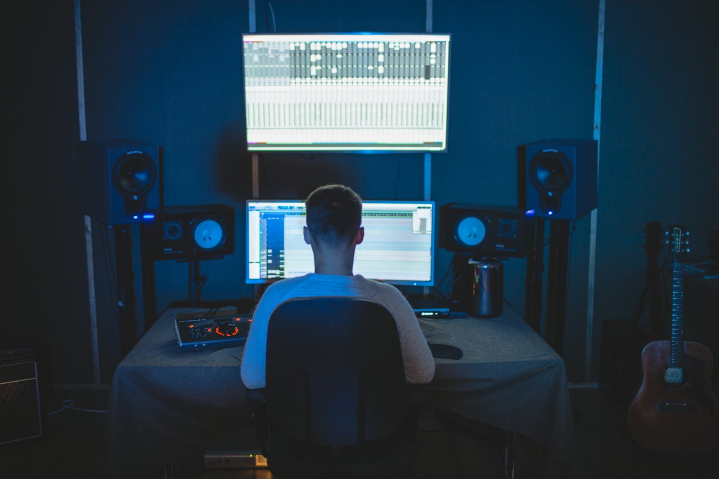 Hombre trabajando en un escritorio en un estudio de grabación con poca luz.
