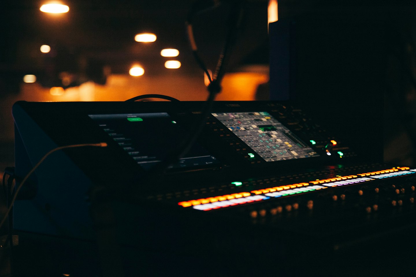 Consola de mezcla de audio digital con botones y pantallas brillantes.